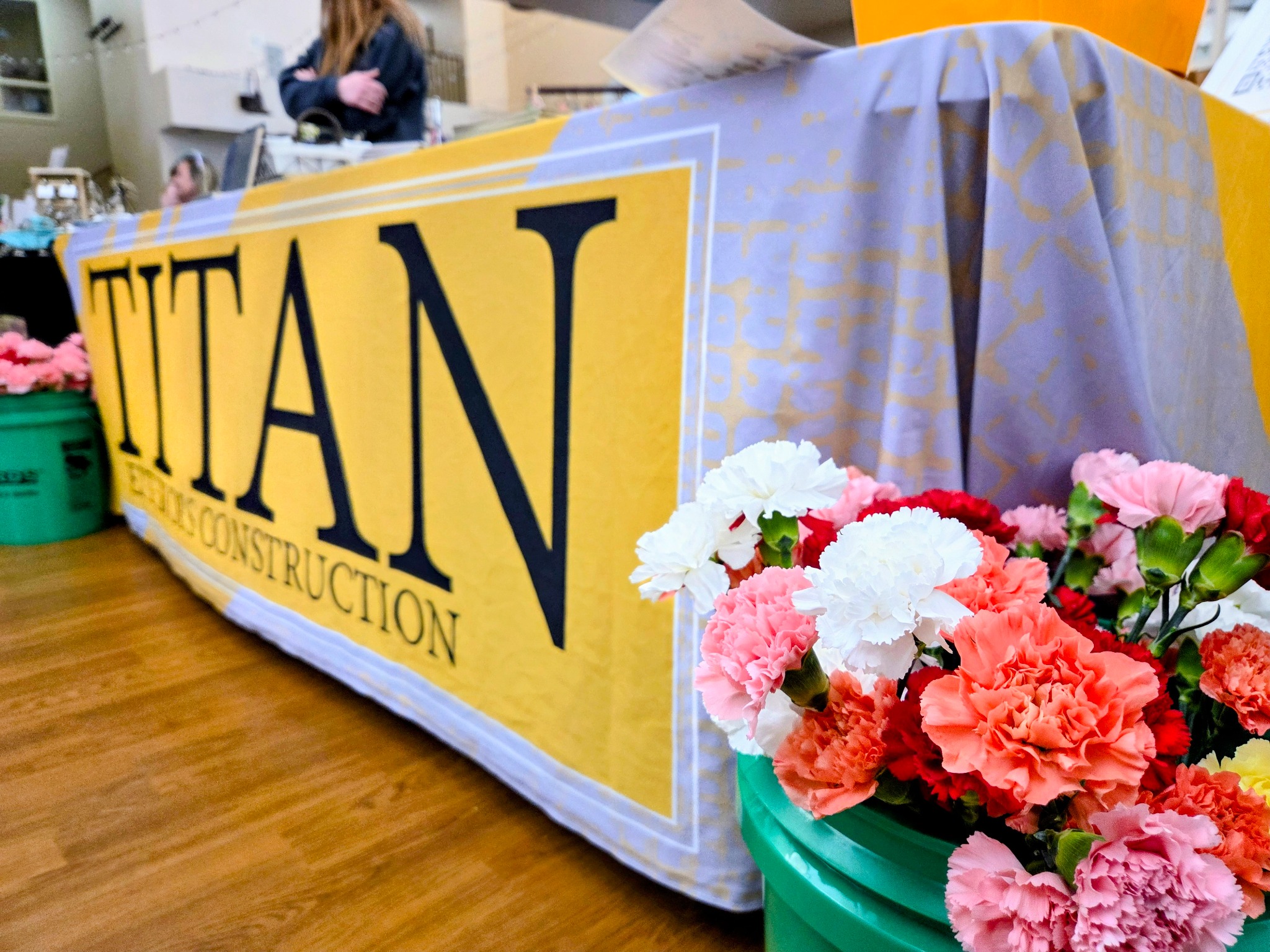 Titan Exteriors and Construction booth decorated with colorful flowers